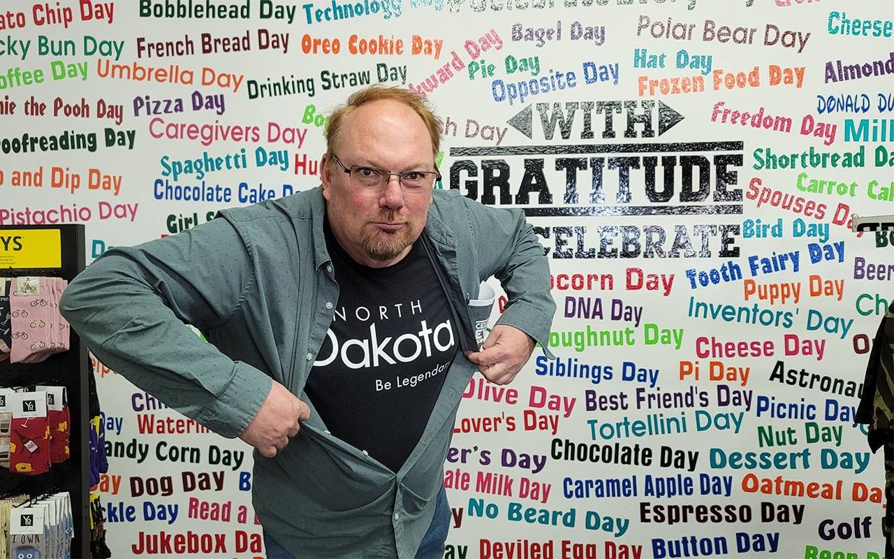 A man standing in front of a wall with days of celebration. Next Avenue