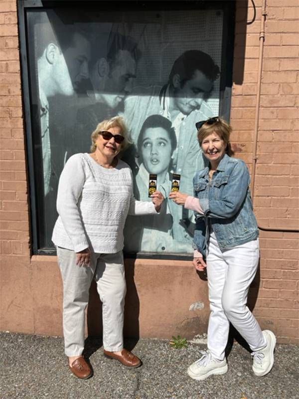 Two people smiling in front of a photo of Elvis. Next Avenue