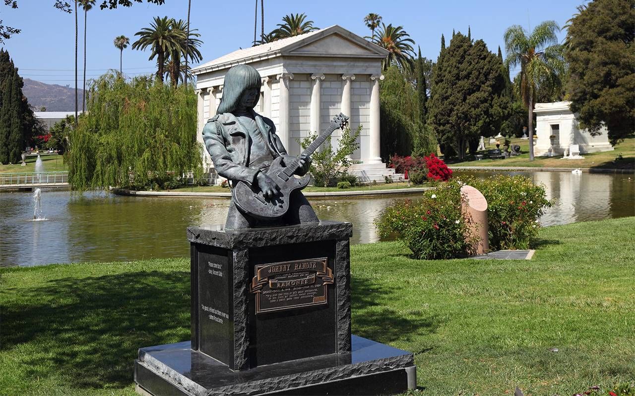 A tombstone with a sculpture of a man playing a guitar. Next Avenue, gravestone tourism