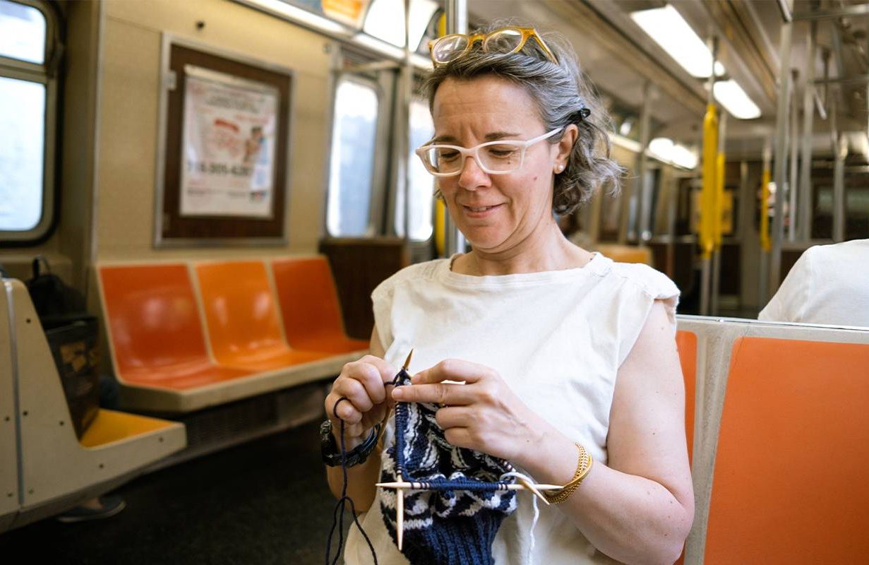 A woman knitting on the subway. Next Avenue