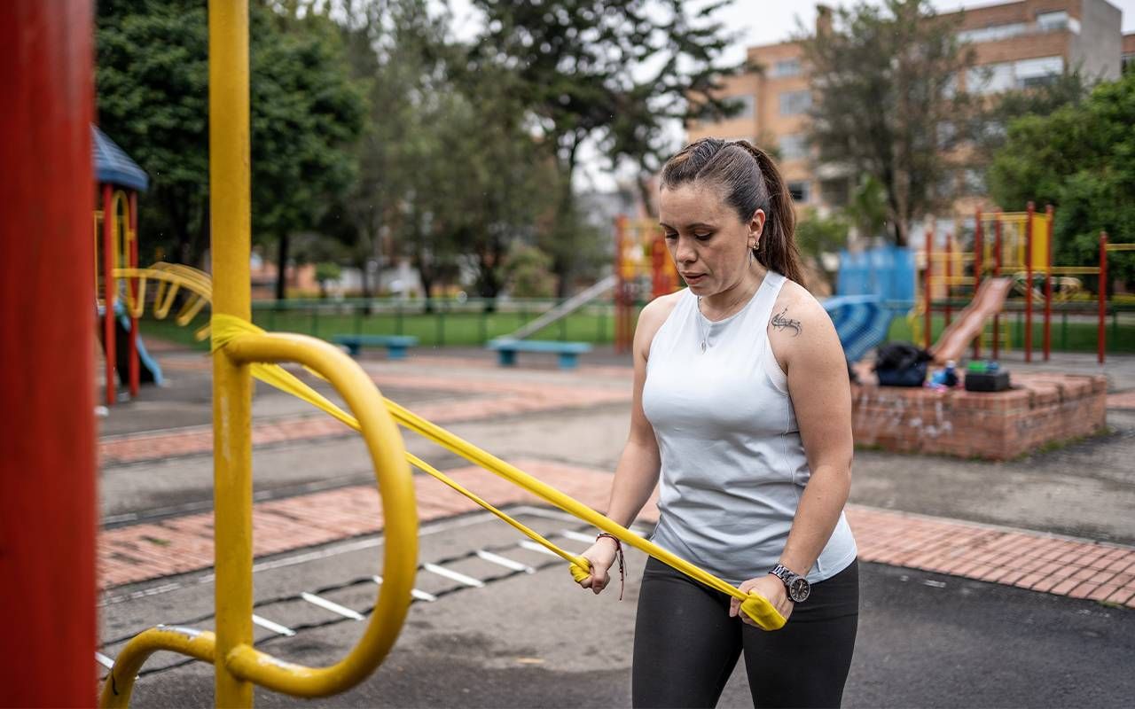 A woman using resistance bands doing strength training at a public park. Next Avenue