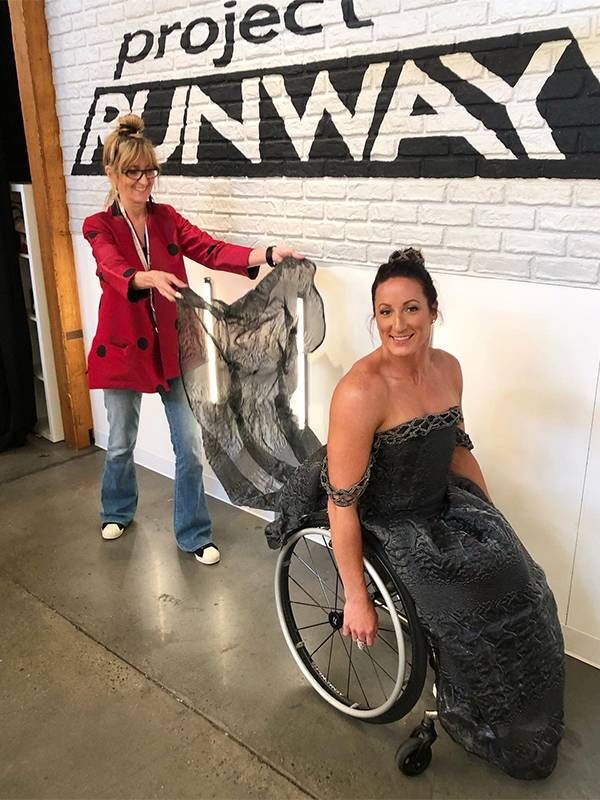 A fashion designer holding the train of a gown for a model who uses a wheelchair. Next Avenue