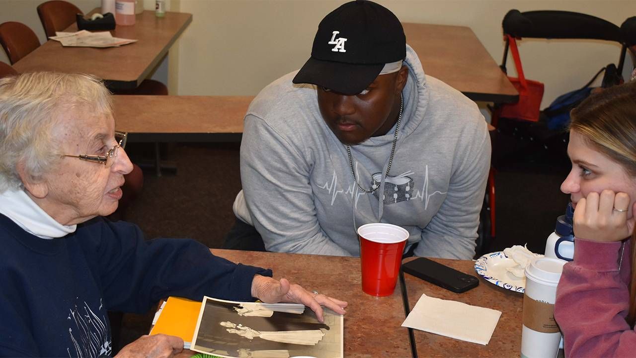 An older adult with students in a college classroom. Next Avenue