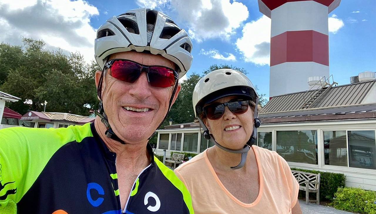 An older couple smiling while on a bike ride. Next Avenue