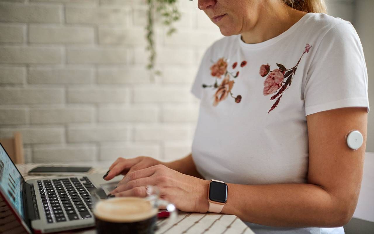 A woman wearing a continuous glucose monitor at home. Next Avenue