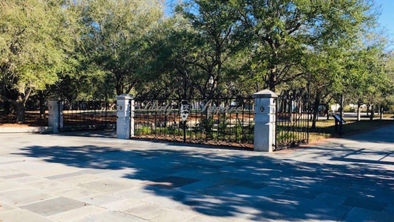 An illegible sign on a wrought iron fence. Next Avenue