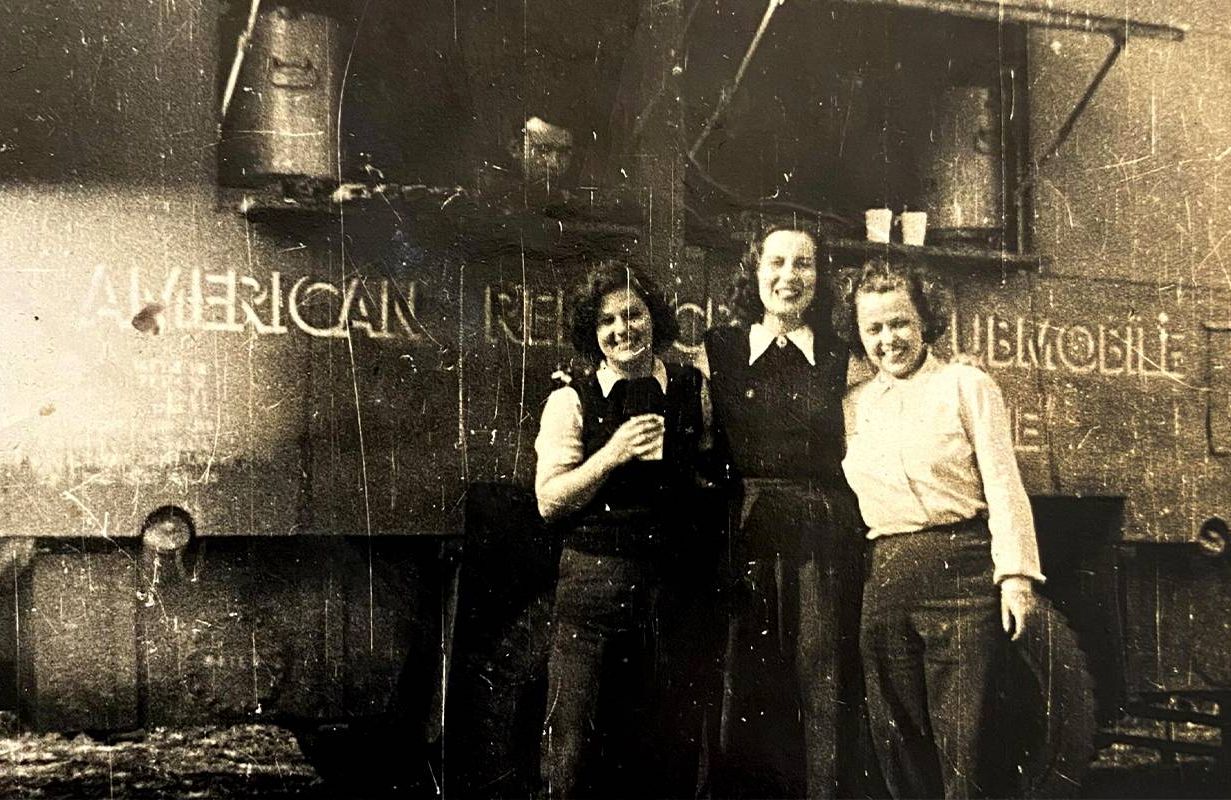 A vintage photo of three women smiling in front of a truck. Next Avenue