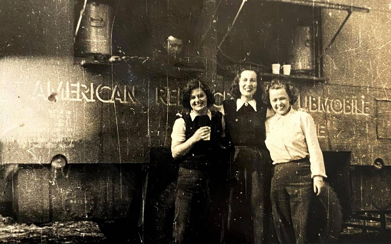 A vintage photo of three women smiling in front of a truck. Next Avenue