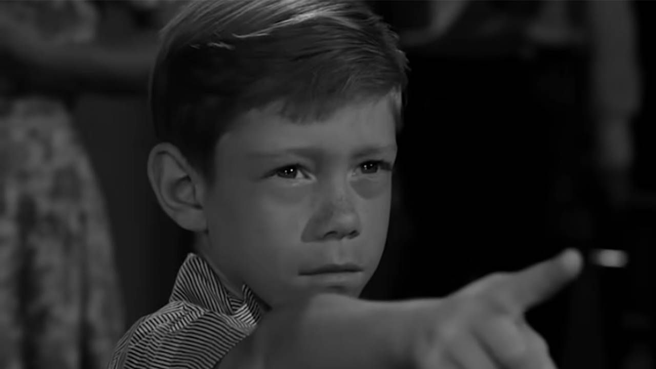 A black and white photo of a young boy pointing his finger. Next Avenue, twilight zone