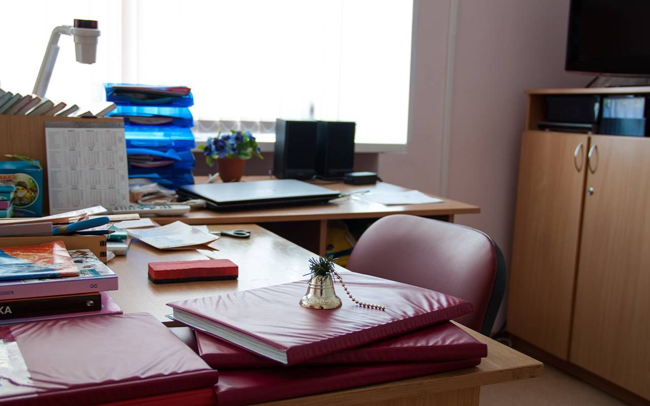 A principal's desk with belongings and an empty chair. Next Avenue