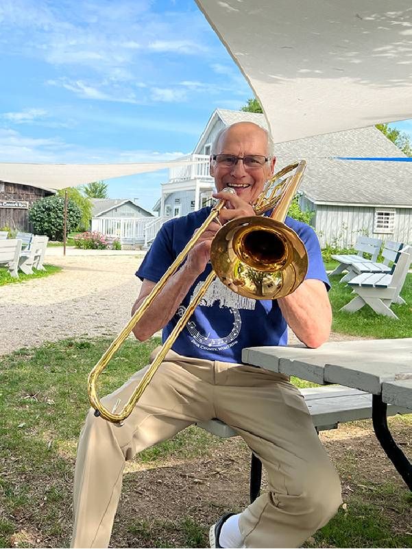 A man holding up a trombone. Next Avenue, Door County Wisconsin Travel