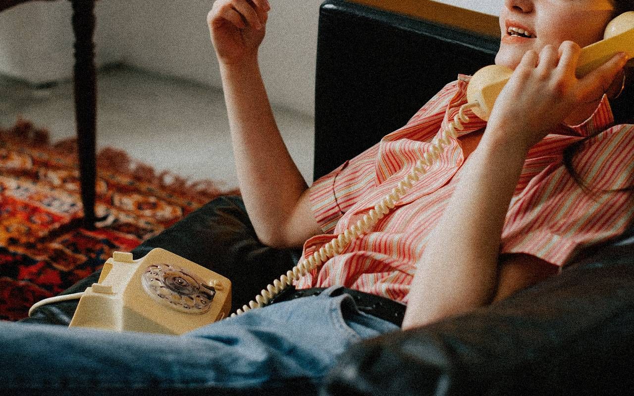 A teen girl talking on a corded landline telephone. Next Avenue