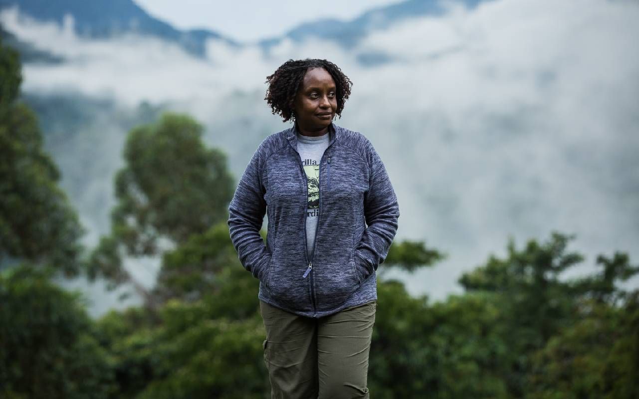 A woman walking down a path with a dense jungle behind her. Next Avenue