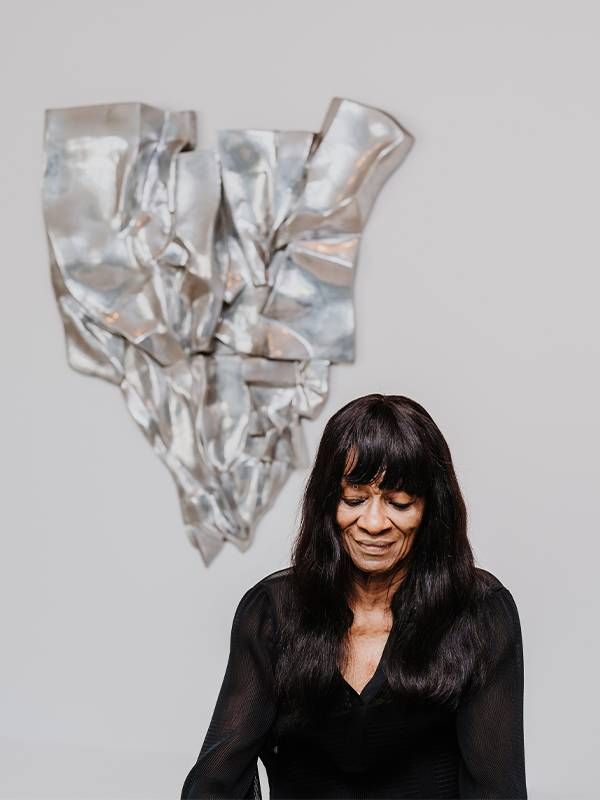 Portrait of a woman in front of a silver sculpture. Next Avenue, Barbara Chase-Riboud