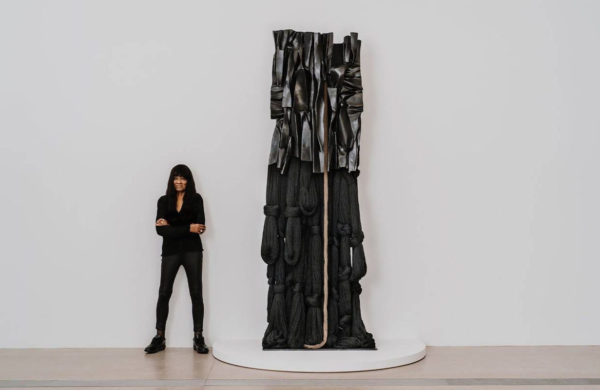A woman standing next to a tall sculpture. Next Avenue, Barbara Chase-Riboud