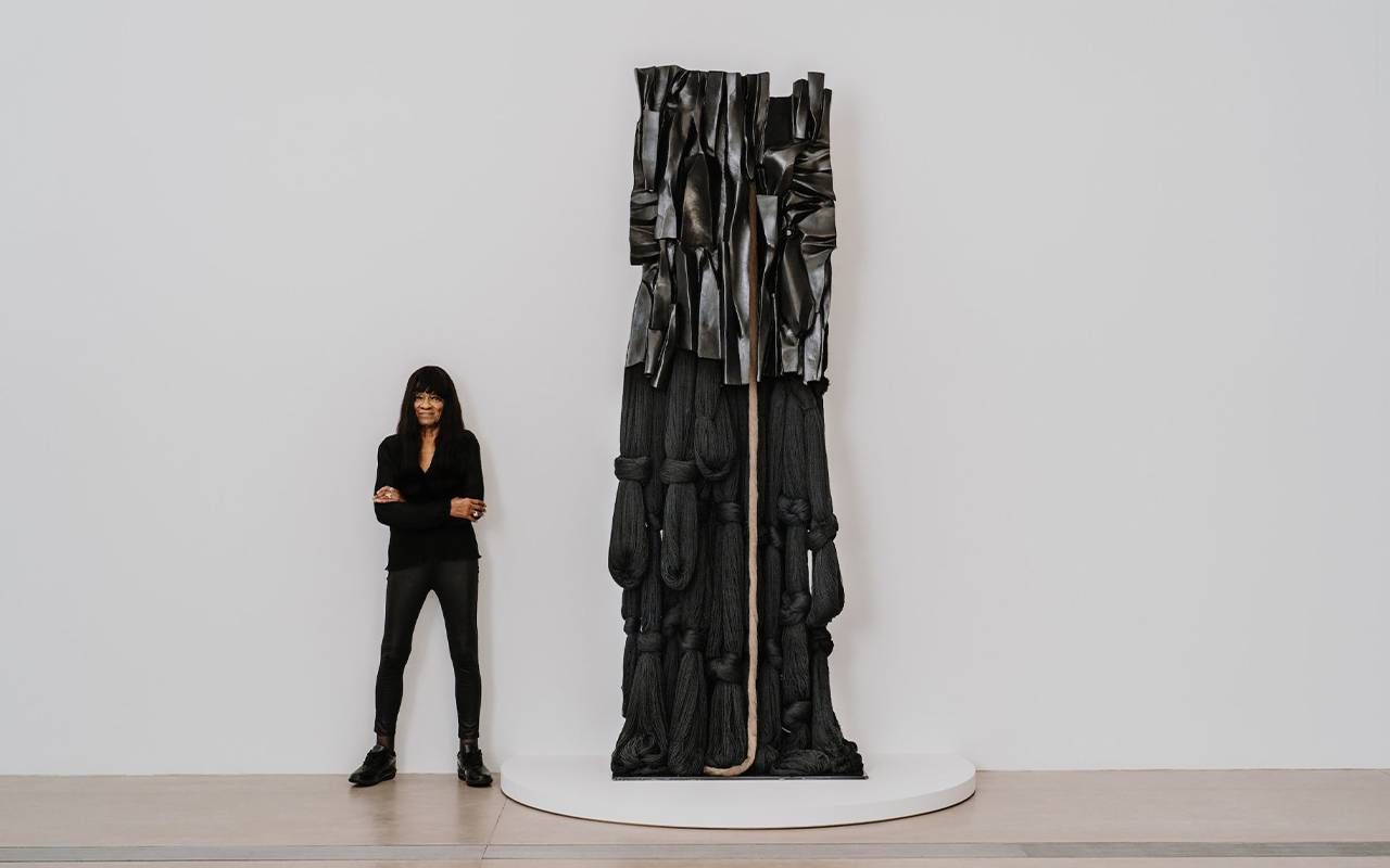 A woman standing next to a tall sculpture. Next Avenue, Barbara Chase-Riboud