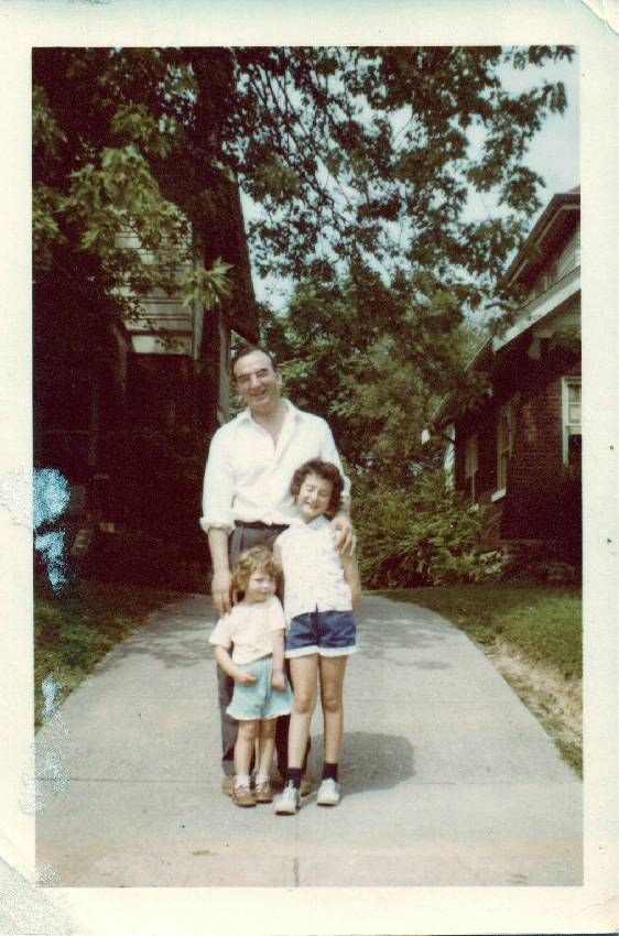 A old photo of a man standing in a driveway with his two daughters. Next Avenue