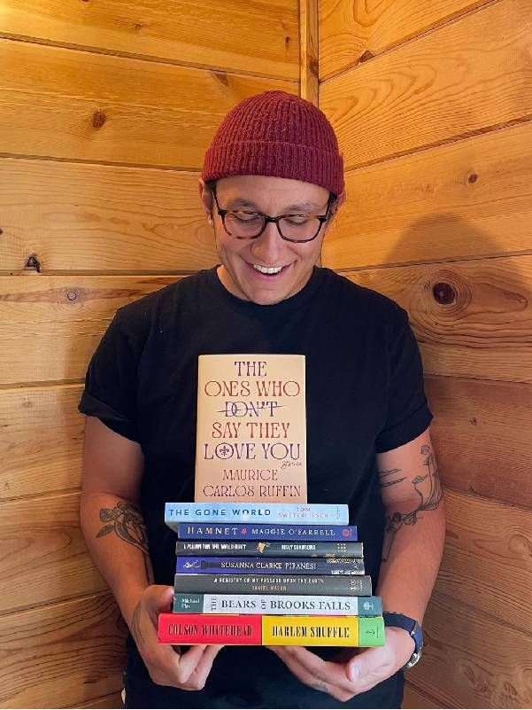 Headshot of a person holding several books. Next Avenue