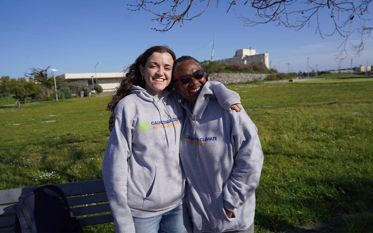 A young person and an older adult smiling with their arms around each other. Next Avenue