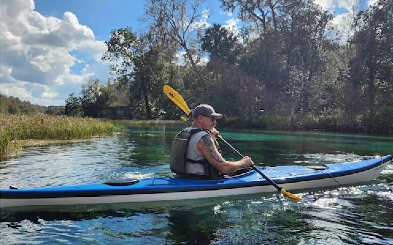 A man kayaking in a clear river. Next Avenue