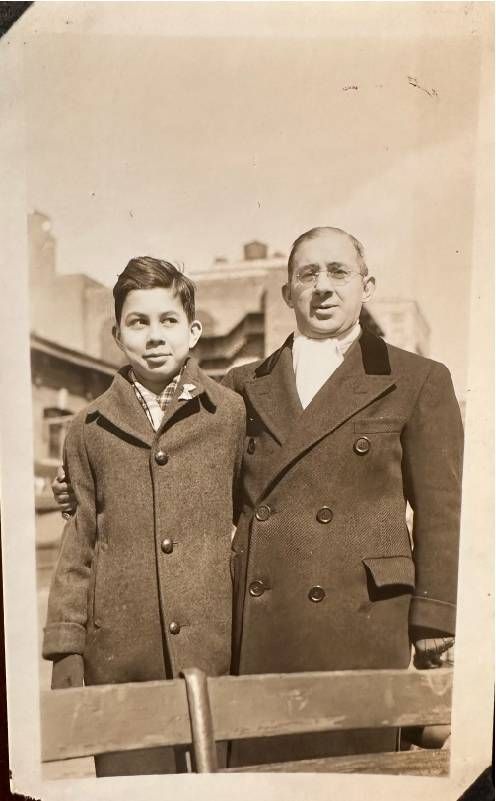 An old photo of a man standing next to a young boy. Next Avenue