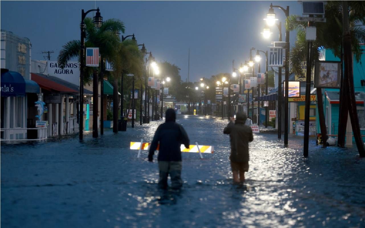People wading through flood waters on a main street in Florida. Next Avenue