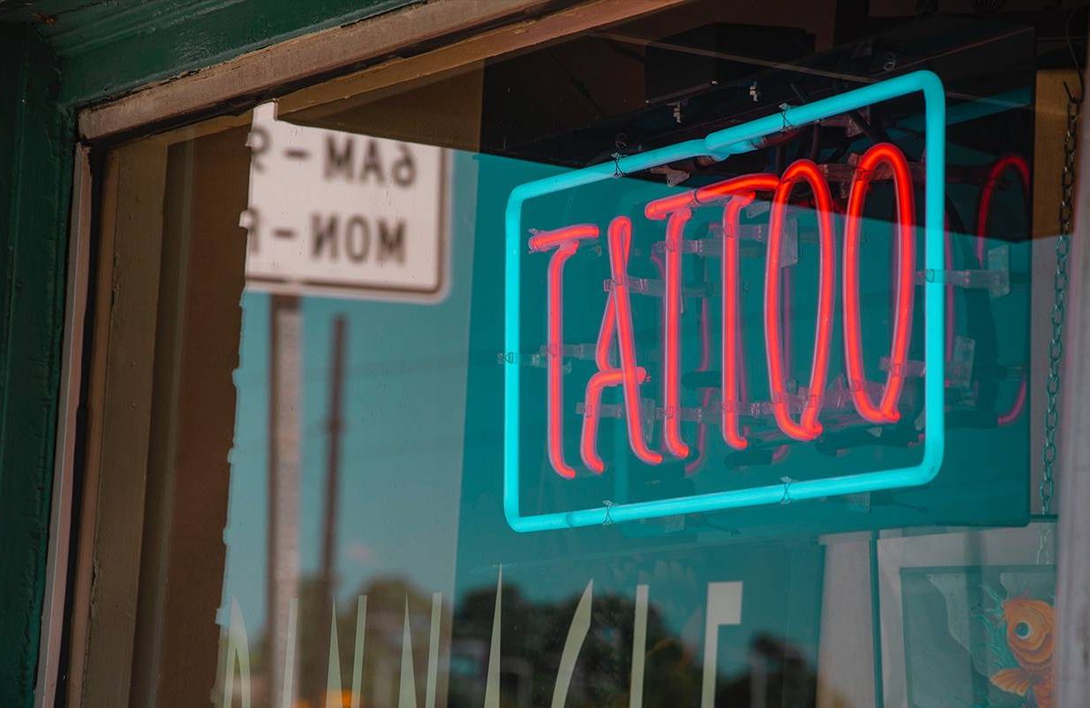 A close up of a tattoo shop's sign. Next Avenue