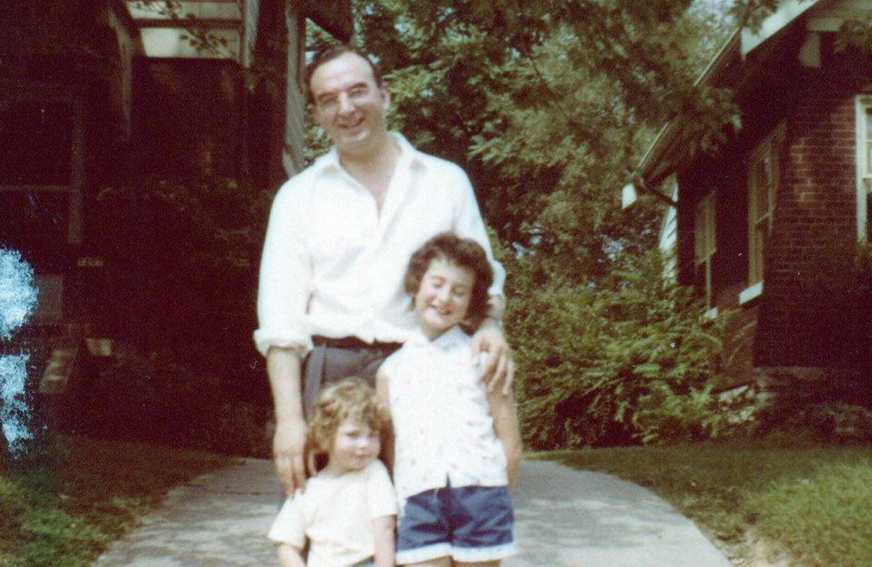 A old photo of a man standing in a driveway with his two daughters. Next Avenue