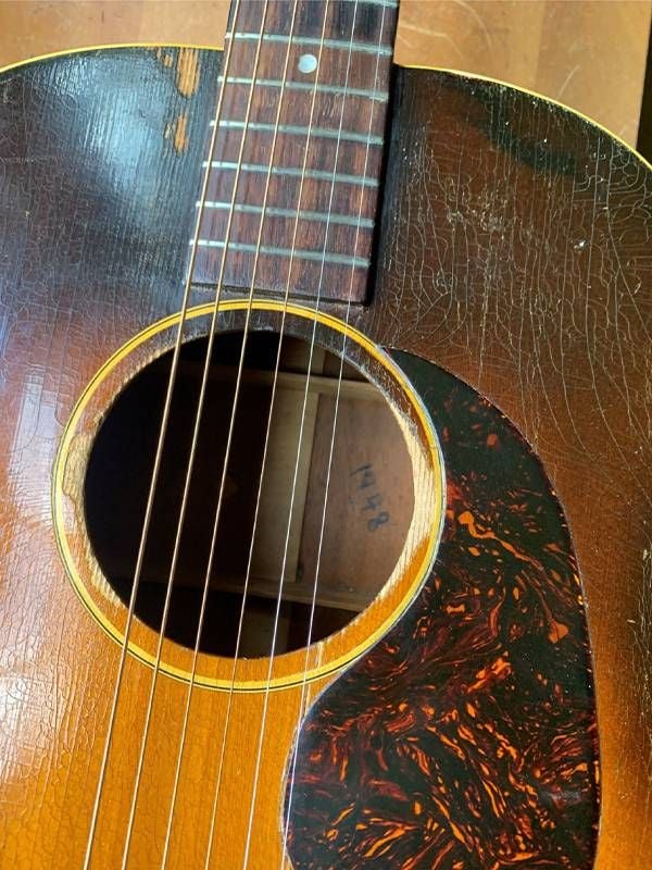 A close up of an old scratched up guitar. Next Avenue