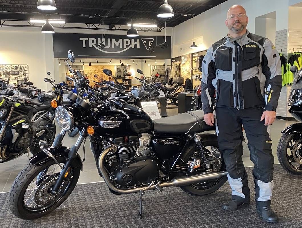 A man wearing motorcycle gear standing next to a big new motorcycle. Next Avenue