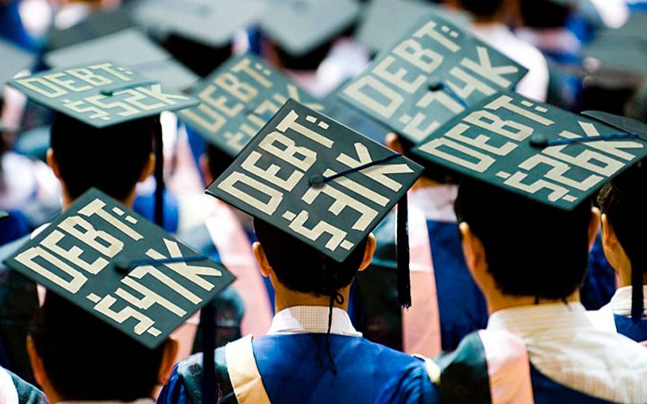 Students at a college graduation ceremony with the amount of their debt written on their graduation caps. Next Avenue