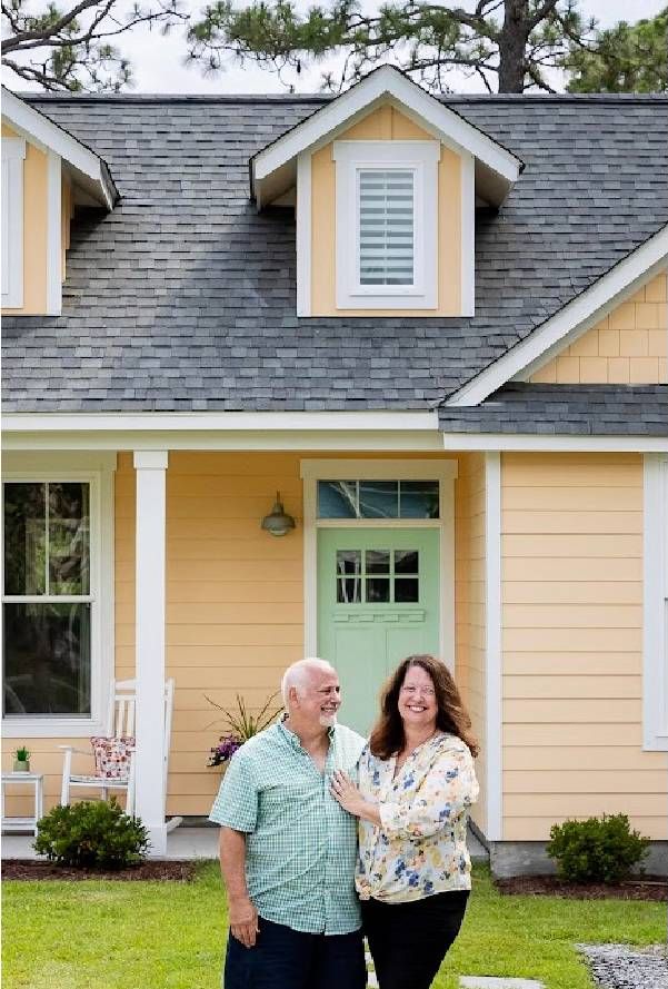 A couple standing in front of a bright peach colored house. Next Avenue, solar, retirement