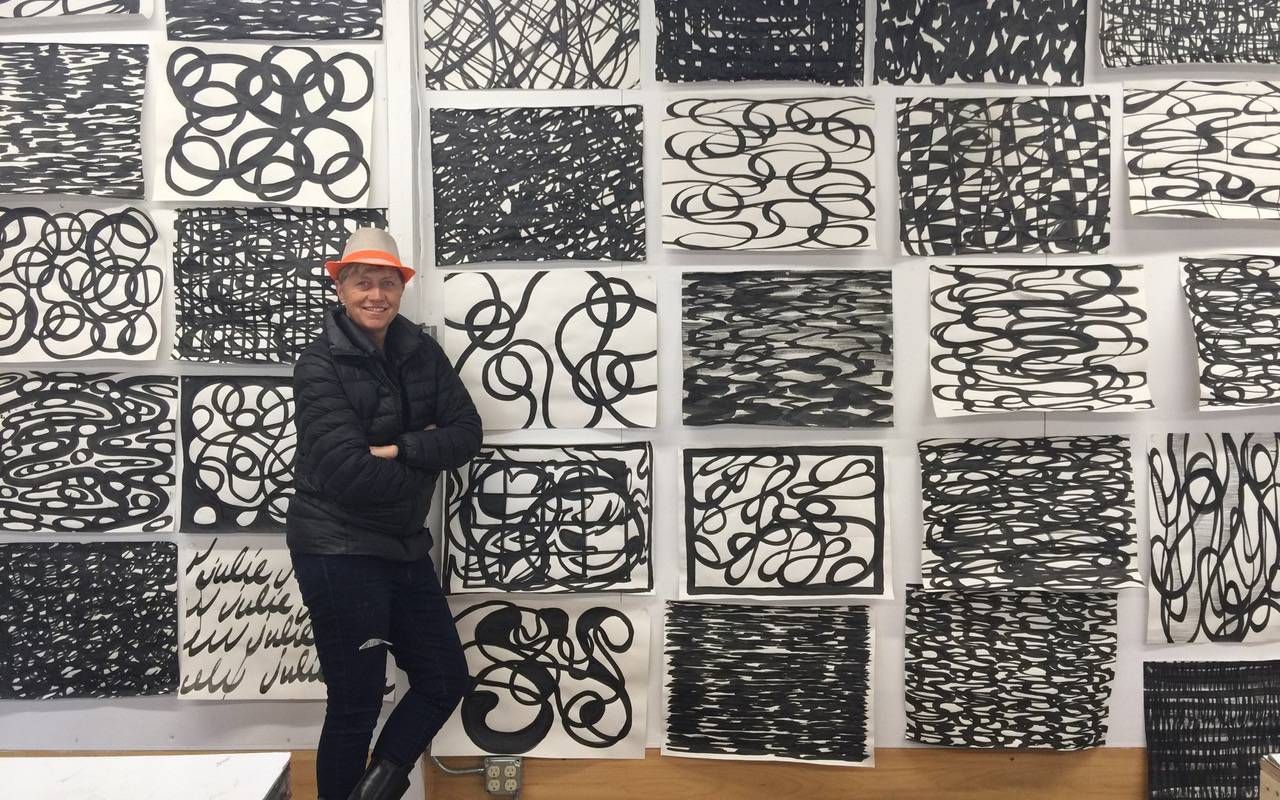 An artist standing in front of a large black and white art piece. Next Avenue, Maine, Artists