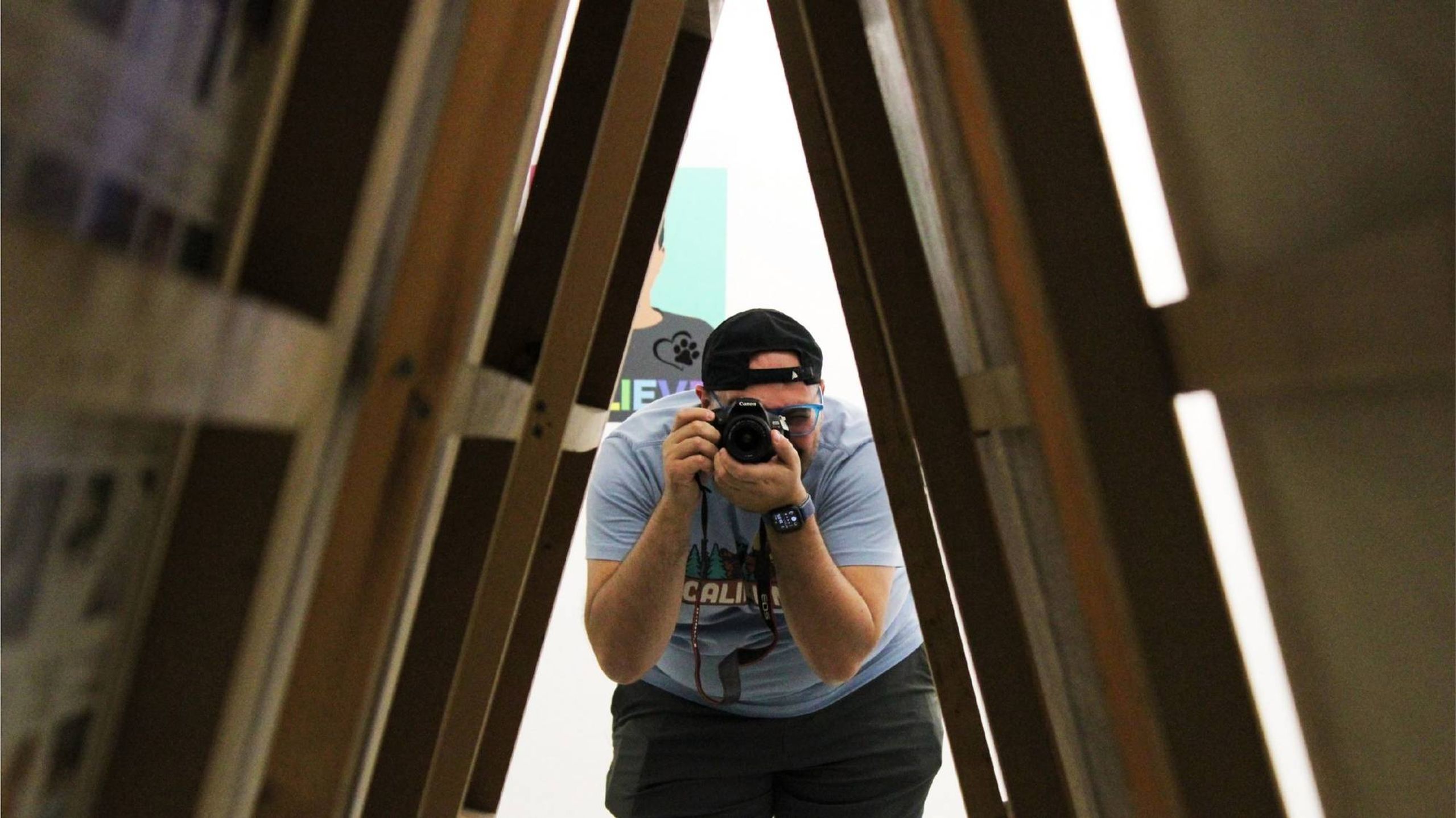 A person holding a camera framed by a triangular shape. Next Avenue