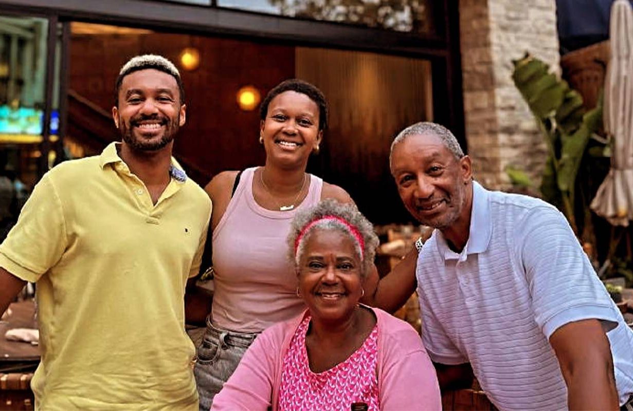A family of four smiling together outside of a restaurant. Next Avenue, family crisis,
