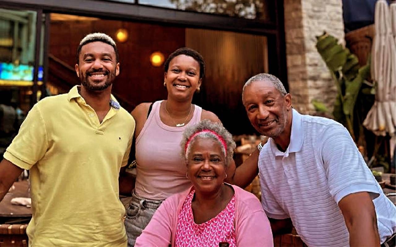 A family of four smiling together outside of a restaurant. Next Avenue, family crisis,