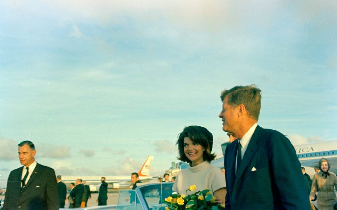 Two people walking on an airport tarmac. Next Avenue, Sixty Years jfk Assassination