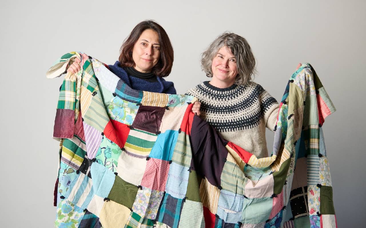 Two women holding up a quilt. Next Avenue, quilting, The Loose Ends Project