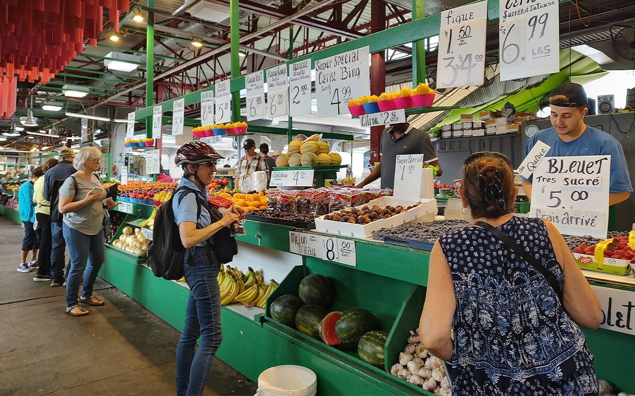 Customers approaching stands in an open air market. Next Avenue