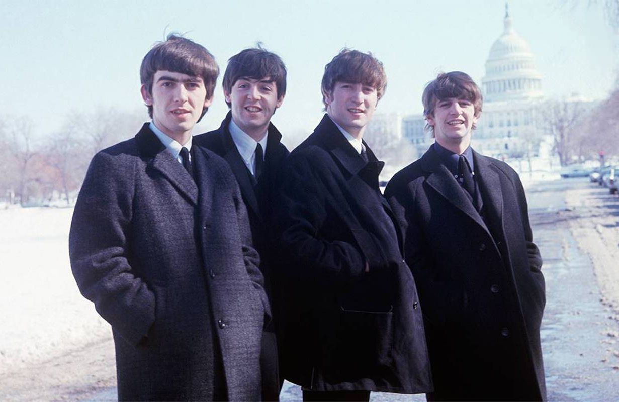 The Beatles standing outside with the U.S. Capital building in the background. Next Avenue