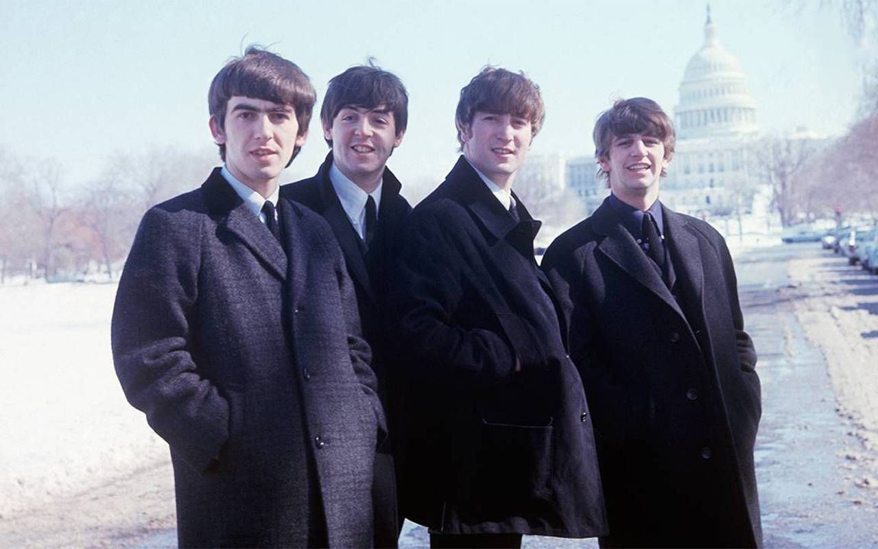 The Beatles standing outside with the U.S. Capital building in the background. Next Avenue