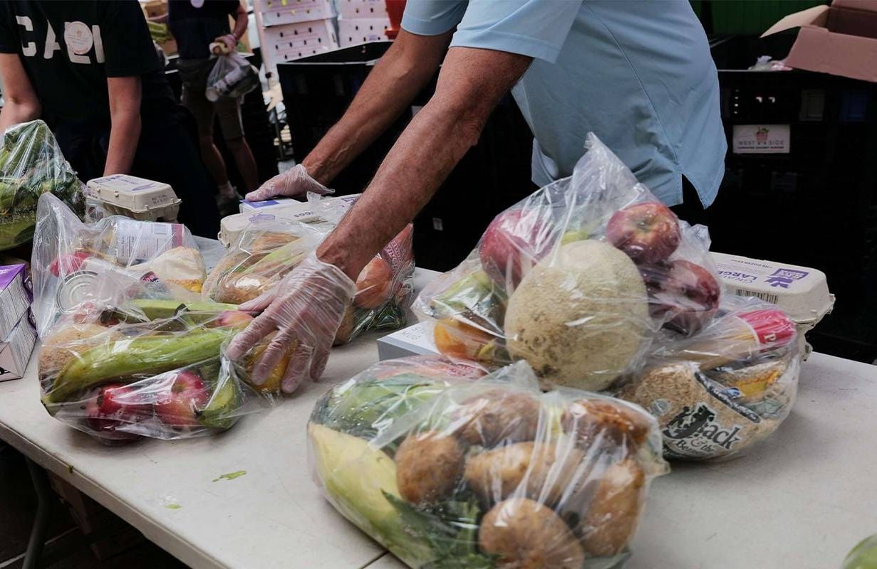 A close-up of people putting together bags of fresh food for older adults living in poverty. Next Avenue
