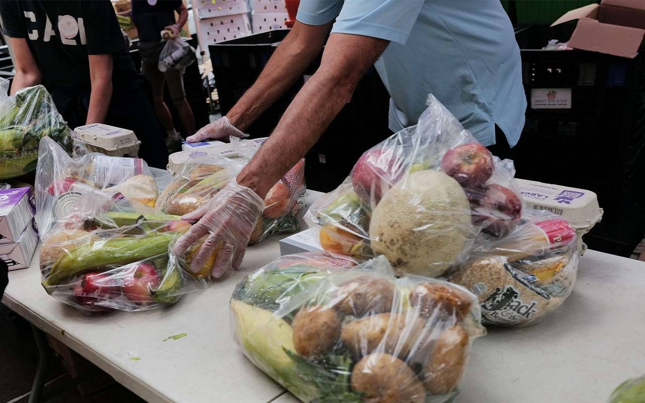 A close-up of people putting together bags of fresh food for older adults living in poverty. Next Avenue