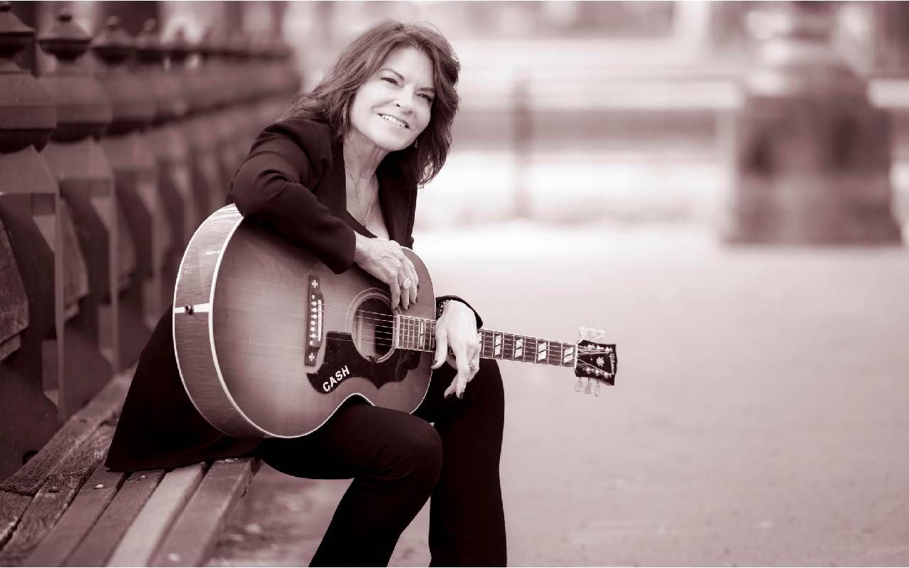 A photo of Rosanne Cash holding a guitar. Next Avenue