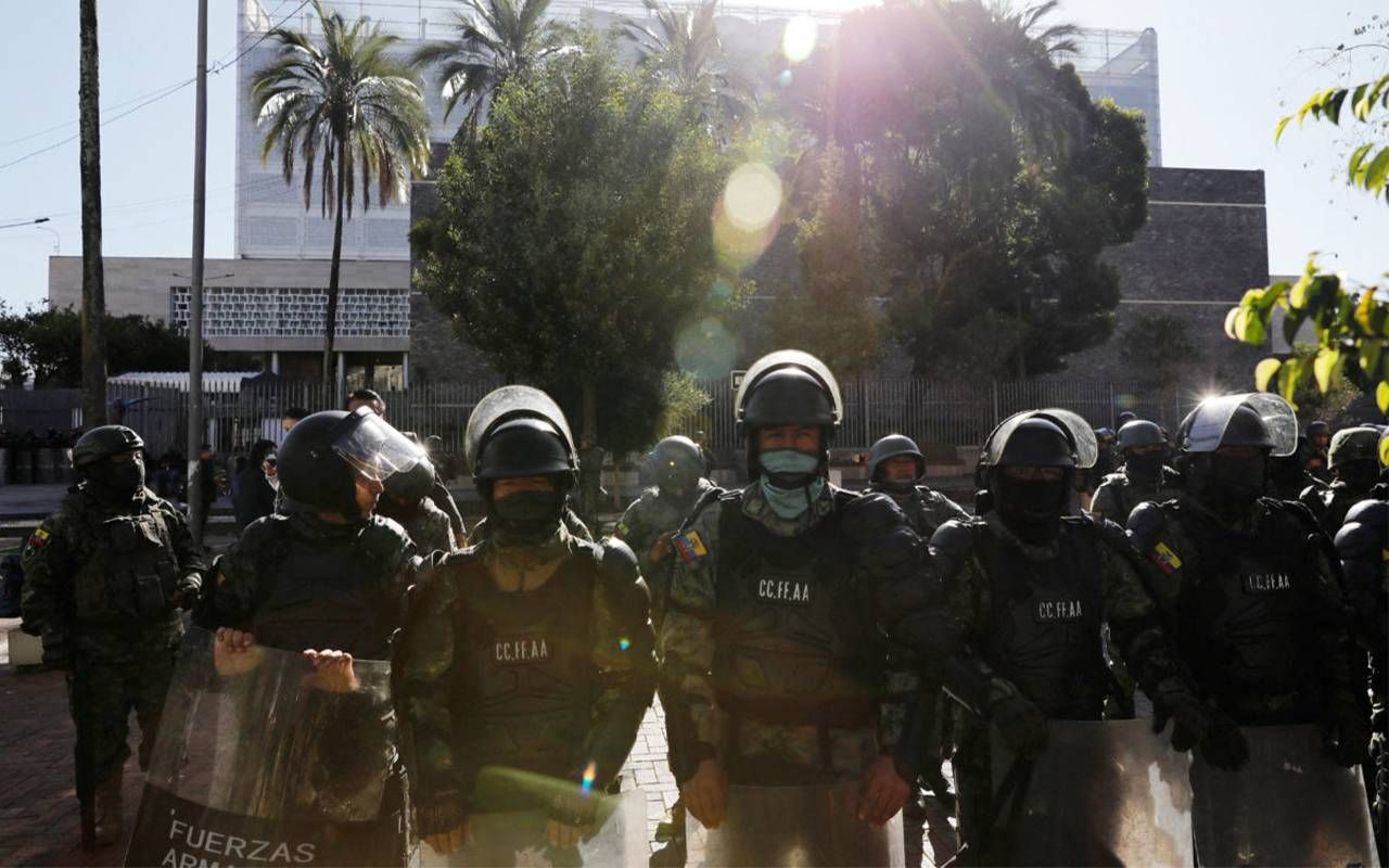 Police wearing military-style uniforms and riot gear standing in front of a building. Next Avevnue