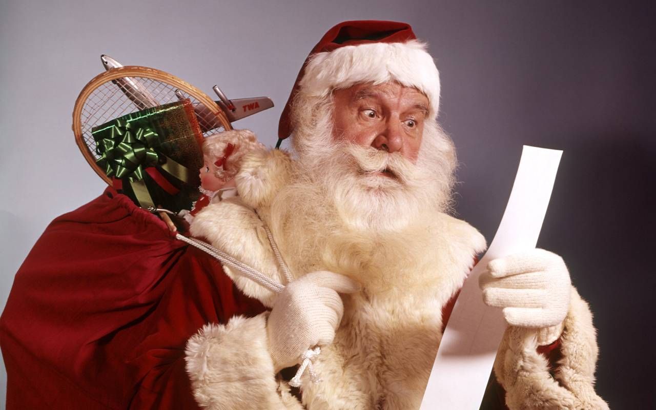 A vintage looking santa reading a Christmas list. Next Avenue
