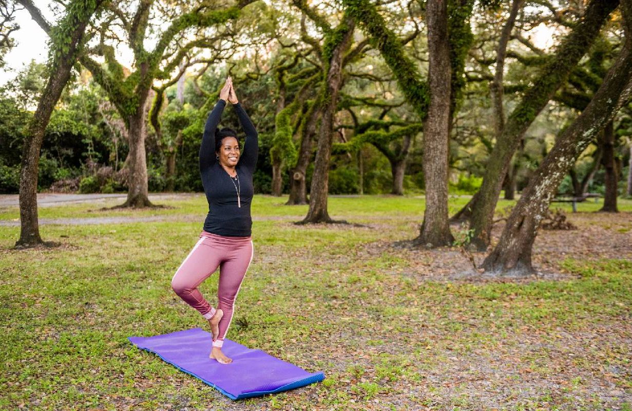 A woman practicing yoga in a park. Next Avenue, balance exercises