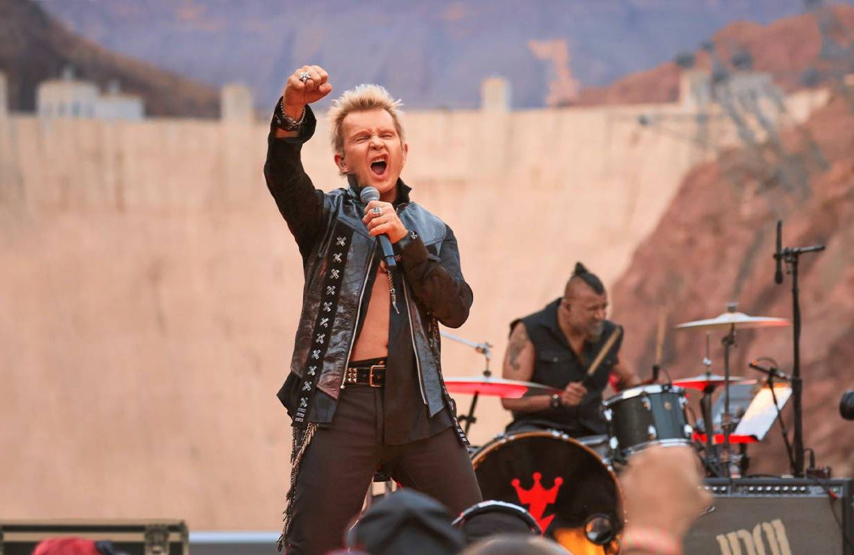 Billy Idol holding a microphone while performing on stage. Next Avenue