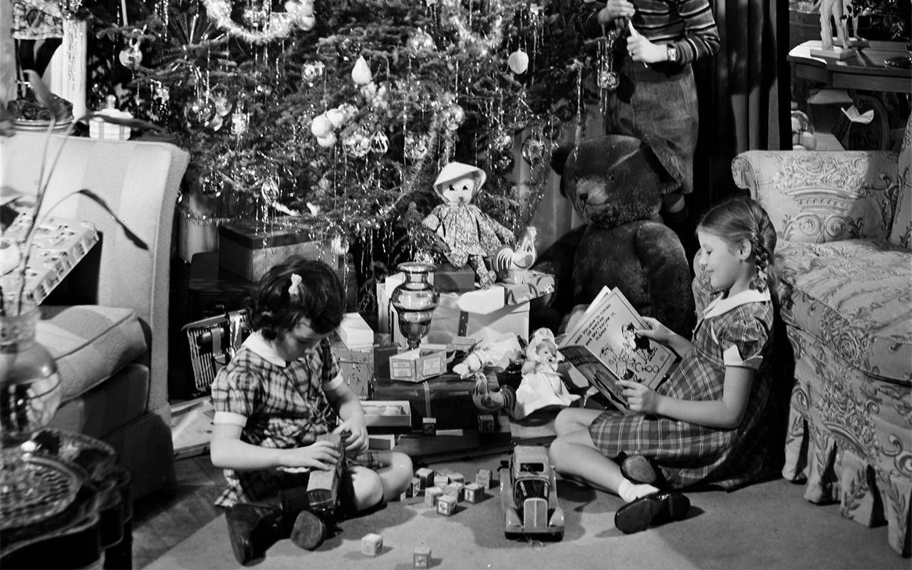 A vintage photo of kids opening presents at Christmas. Next Avenue
