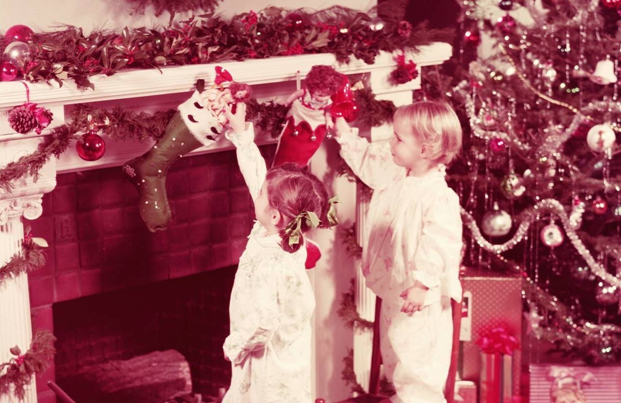 A vintage photo of two children looking at toys in their stockings. Next Avenue, christmas memories, childhood